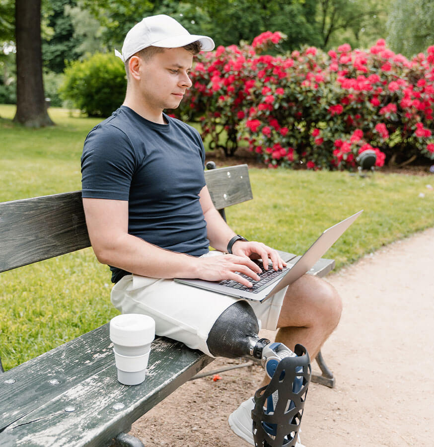 man with prosthesis on his leg sitting with a laptop doing remote work